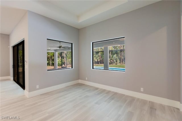 spare room with a raised ceiling, ceiling fan, and light wood-type flooring