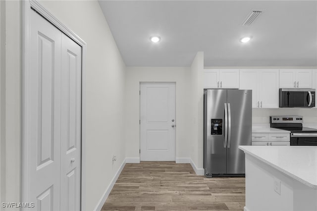 kitchen with white cabinets, light wood-type flooring, and stainless steel appliances