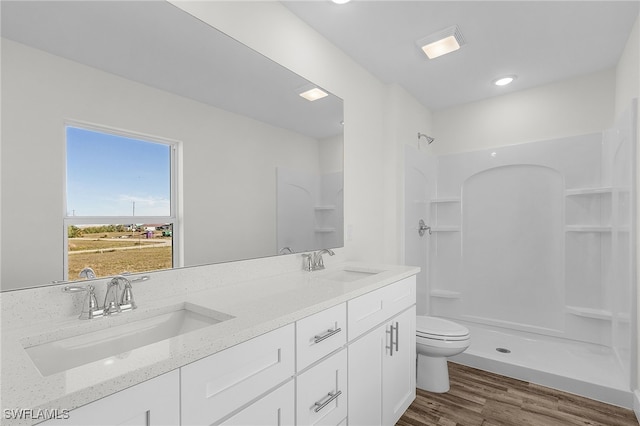 bathroom featuring hardwood / wood-style flooring, vanity, toilet, and a shower