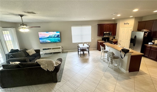 tiled living room featuring ceiling fan and a textured ceiling