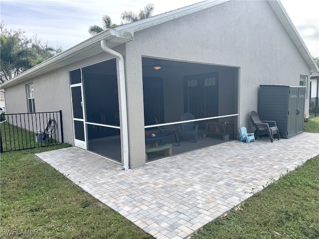 rear view of property featuring a sunroom, a yard, and a patio