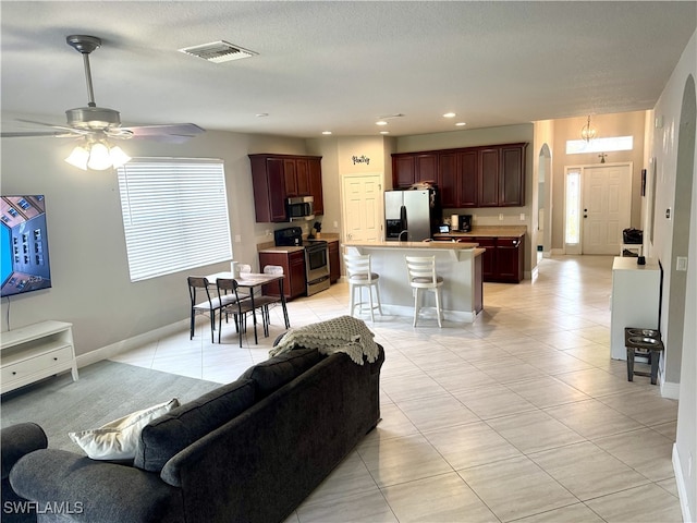 living room with a textured ceiling, ceiling fan, and light tile patterned flooring