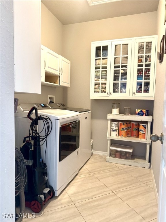 clothes washing area with cabinets, separate washer and dryer, and light tile patterned floors