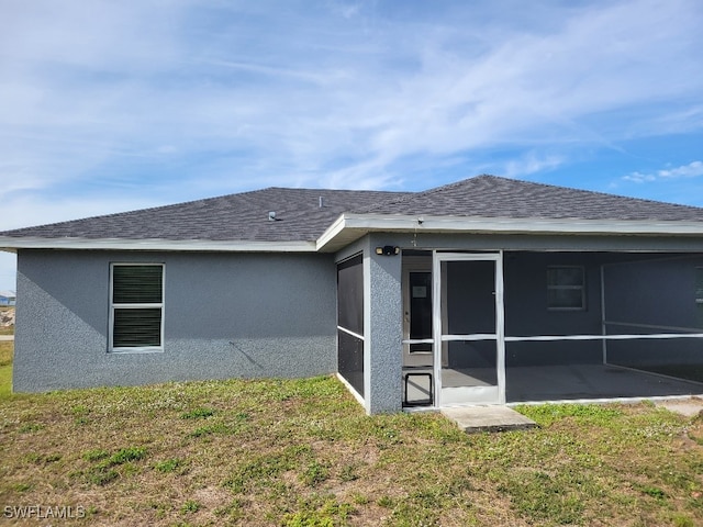 back of house featuring a lawn and a sunroom