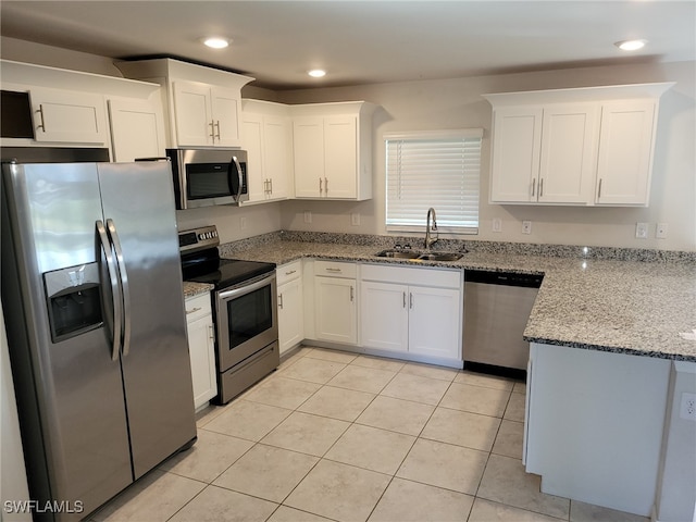 kitchen featuring white cabinetry, sink, light stone counters, light tile patterned floors, and appliances with stainless steel finishes