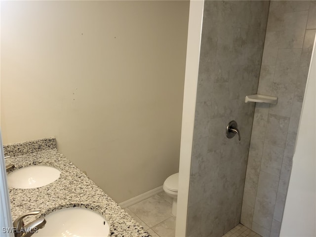 bathroom featuring tile patterned flooring, vanity, toilet, and tiled shower