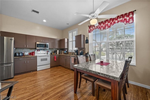 kitchen with tasteful backsplash, dark brown cabinets, stainless steel appliances, sink, and light hardwood / wood-style floors