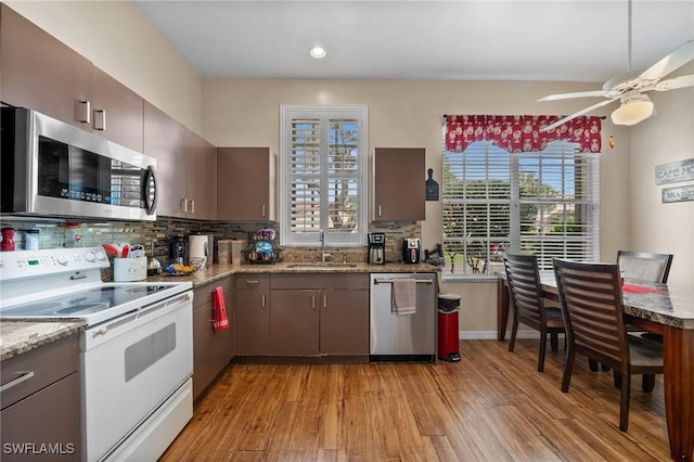 kitchen with sink, appliances with stainless steel finishes, tasteful backsplash, dark brown cabinets, and light hardwood / wood-style floors