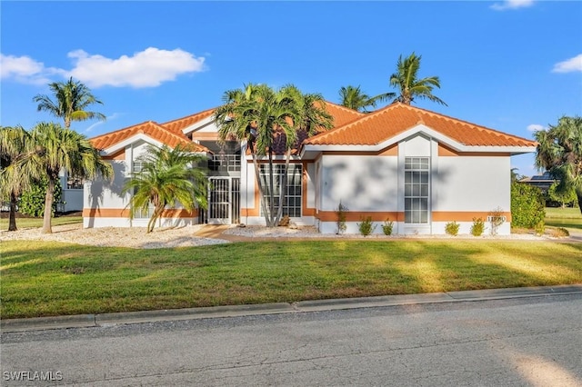 view of front of property with stucco siding, a front lawn, and a tile roof