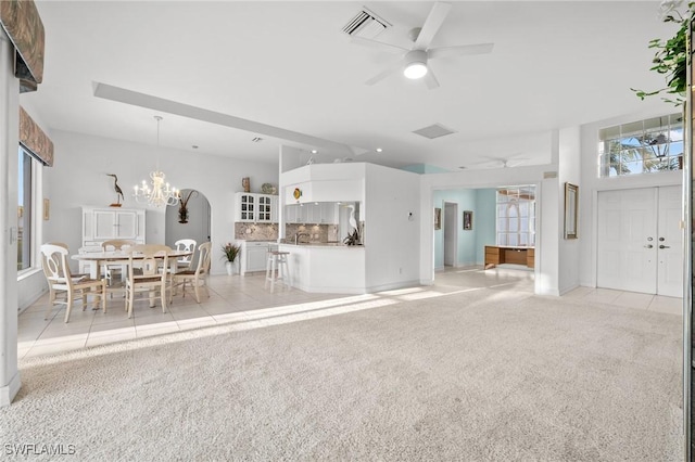 unfurnished living room with ceiling fan with notable chandelier and light colored carpet