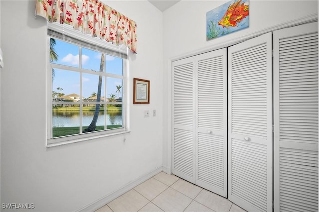 unfurnished bedroom with a water view, multiple windows, a closet, and light tile patterned floors