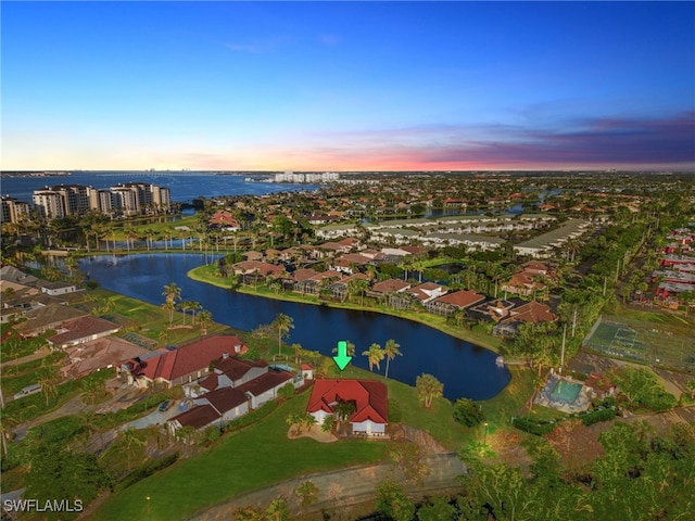 aerial view at dusk featuring a water view