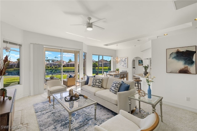 living room with carpet flooring, a ceiling fan, baseboards, and arched walkways