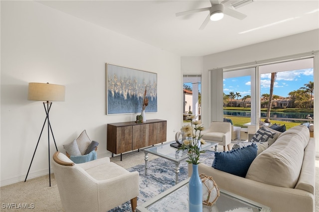 living area with a ceiling fan, baseboards, and carpet floors