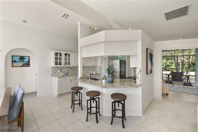 kitchen with visible vents, tasteful backsplash, a breakfast bar, and freestanding refrigerator