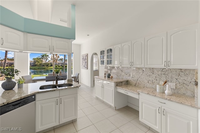 kitchen featuring a sink, decorative backsplash, light stone counters, and stainless steel dishwasher