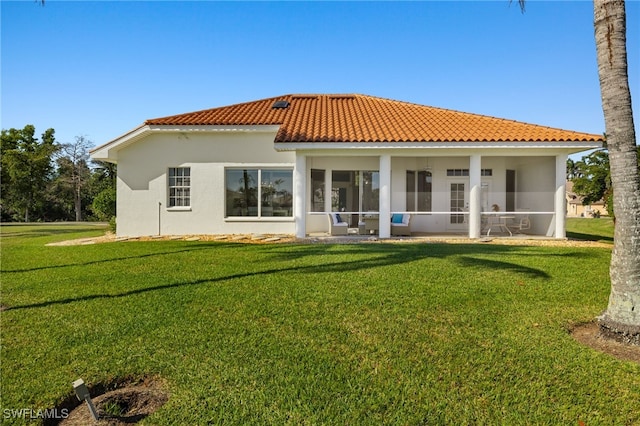 back of house featuring a tile roof, a yard, a sunroom, and stucco siding