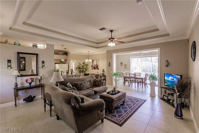 tiled living room with ceiling fan with notable chandelier, ornamental molding, and a tray ceiling