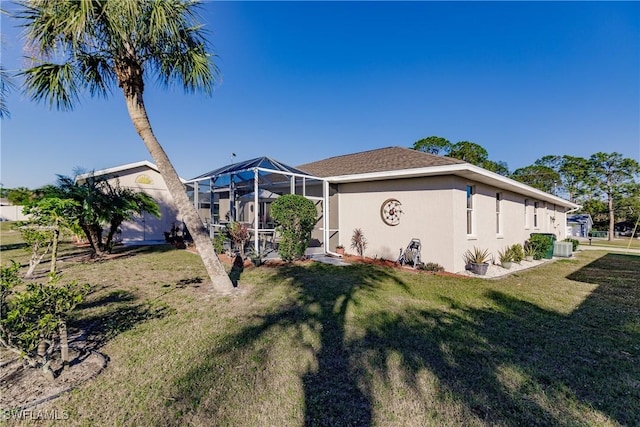 back of property featuring a lanai, a yard, and central air condition unit