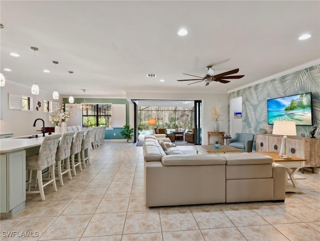 tiled living room with ceiling fan, sink, and crown molding