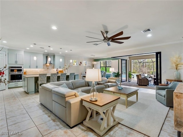 living room featuring ceiling fan, light tile patterned floors, and crown molding