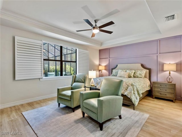 bedroom with light hardwood / wood-style floors, a raised ceiling, ceiling fan, and crown molding