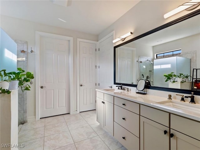 bathroom featuring tile patterned flooring, a tile shower, and vanity