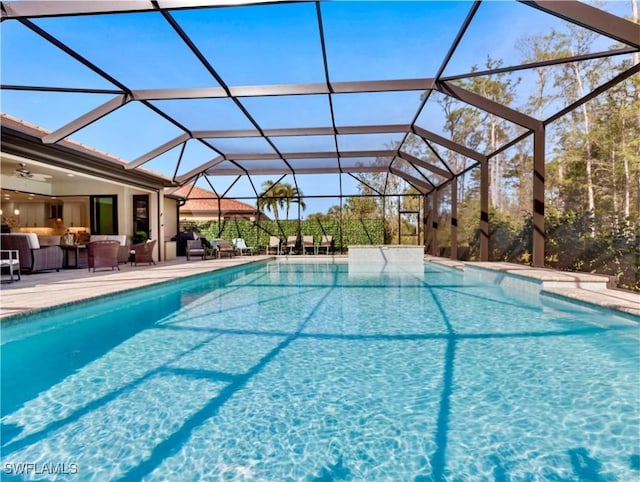 view of swimming pool featuring outdoor lounge area, ceiling fan, a lanai, and a patio