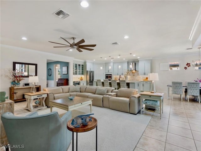 living room featuring light tile patterned floors, ceiling fan, ornamental molding, and sink