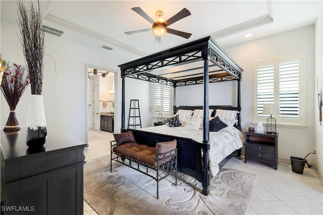 bedroom with ceiling fan, ensuite bathroom, a tray ceiling, light tile patterned floors, and ornamental molding