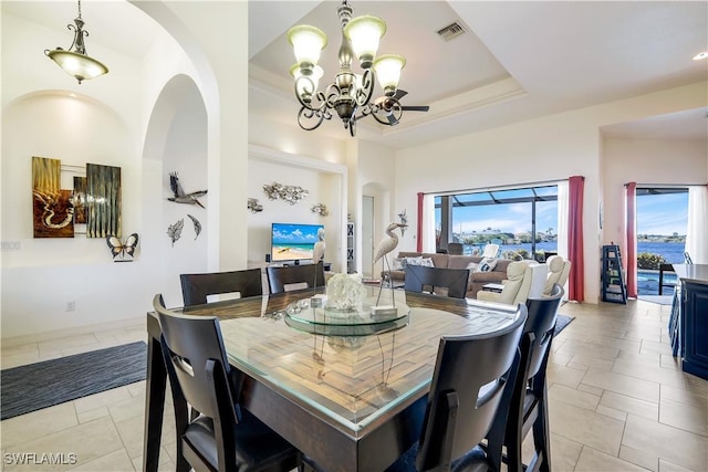 dining area with an inviting chandelier and a raised ceiling