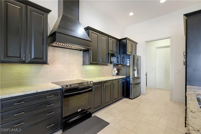 kitchen with tasteful backsplash, light stone countertops, black appliances, and custom range hood