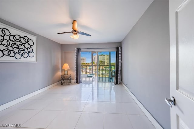 spare room with light tile patterned floors, baseboards, and a ceiling fan