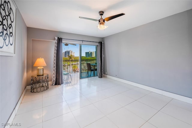 spare room featuring ceiling fan, light tile patterned flooring, and baseboards