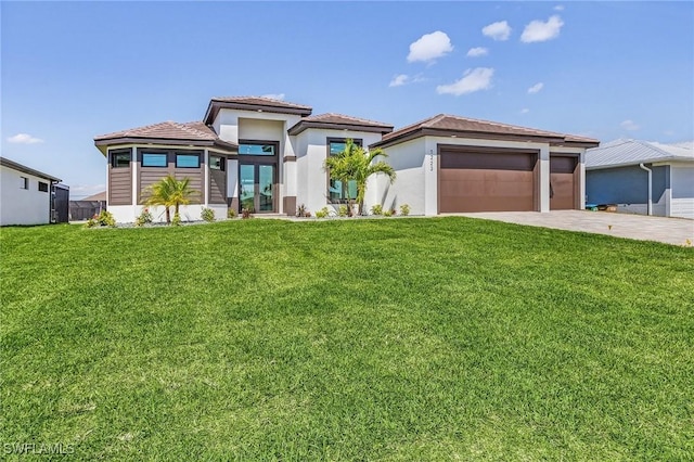 prairie-style house with a front lawn, concrete driveway, stucco siding, french doors, and a garage