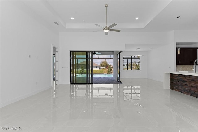 spare room with baseboards, visible vents, a ceiling fan, and a tray ceiling