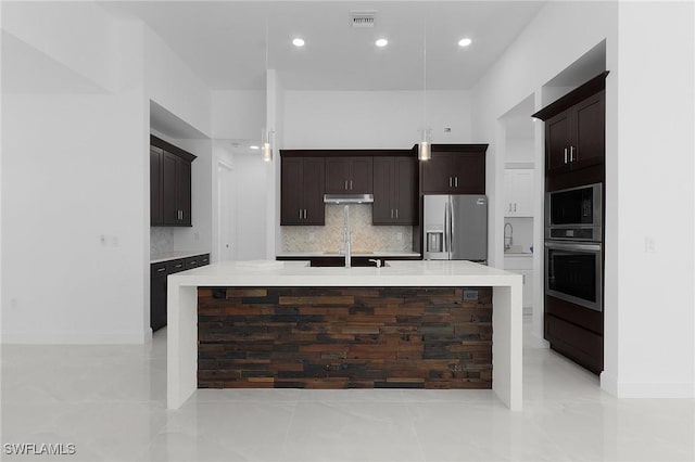 kitchen with visible vents, a large island with sink, decorative backsplash, dark brown cabinets, and appliances with stainless steel finishes