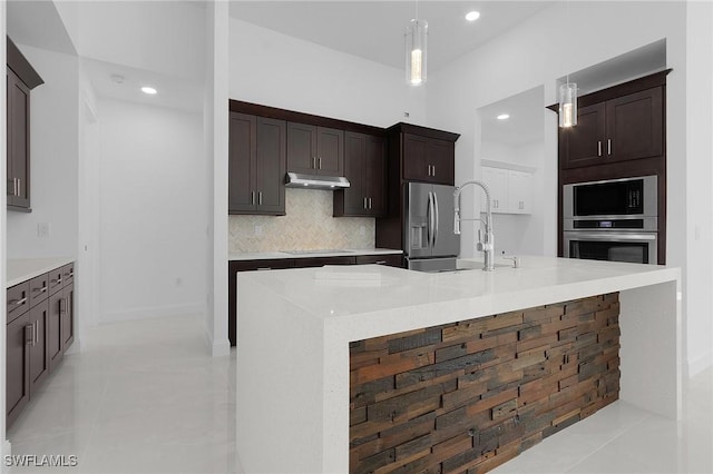 kitchen with under cabinet range hood, tasteful backsplash, dark brown cabinetry, and a sink