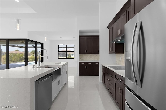 kitchen featuring a sink, dark brown cabinetry, under cabinet range hood, appliances with stainless steel finishes, and backsplash