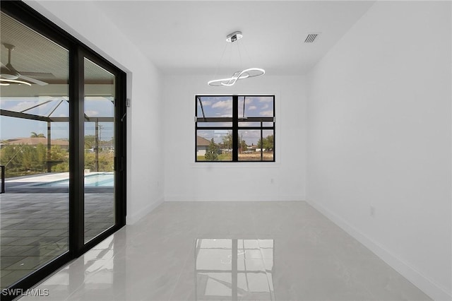 spare room featuring ceiling fan with notable chandelier, baseboards, and visible vents