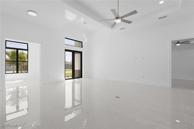 spare room with visible vents, a tray ceiling, a ceiling fan, and a towering ceiling