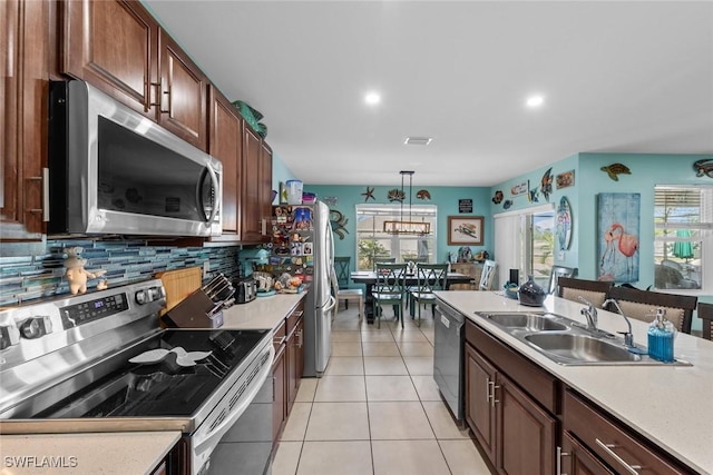 kitchen with appliances with stainless steel finishes, pendant lighting, sink, backsplash, and light tile patterned floors