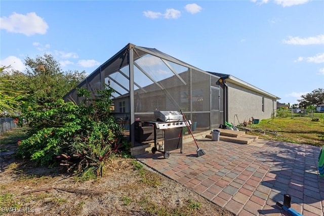 view of patio with area for grilling and a lanai