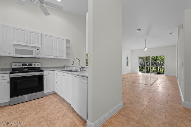 kitchen featuring white appliances, ceiling fan, sink, light tile patterned floors, and white cabinetry