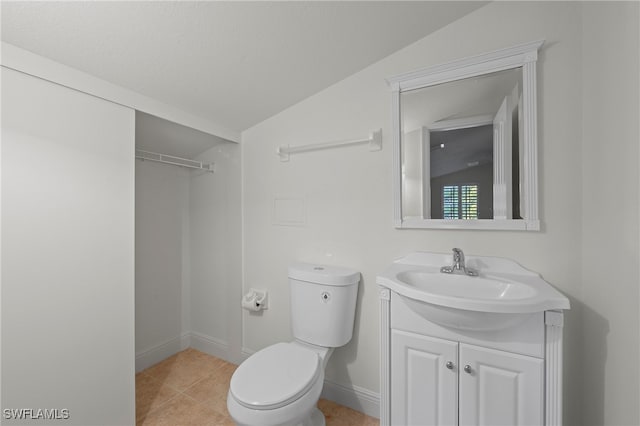 bathroom with toilet, tile patterned floors, vanity, and vaulted ceiling