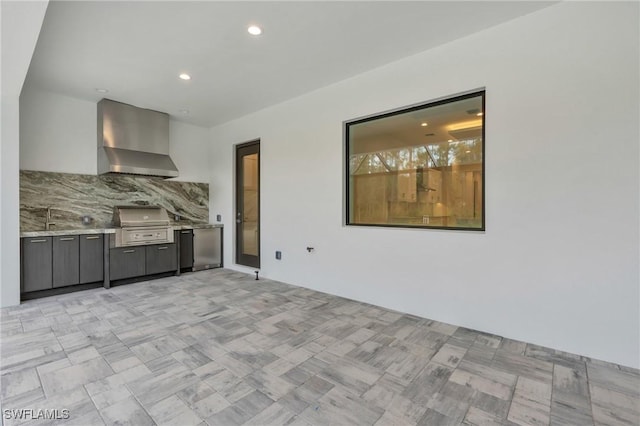 kitchen featuring backsplash, refrigerator, light stone countertops, and wall chimney exhaust hood