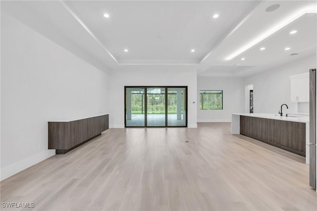 unfurnished living room with light hardwood / wood-style flooring and sink