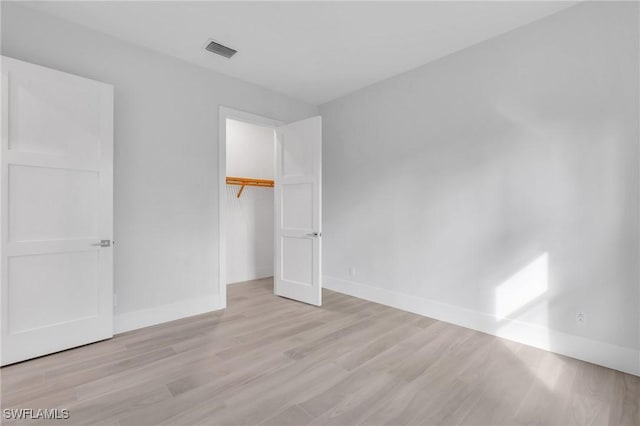 unfurnished bedroom with light hardwood / wood-style floors, a spacious closet, and a closet