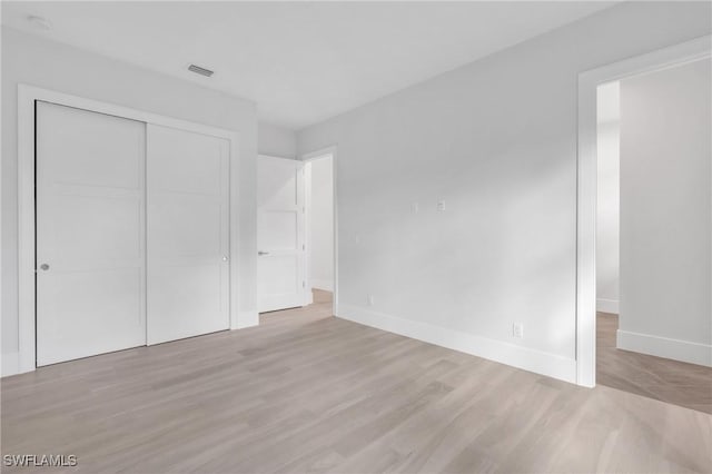 unfurnished bedroom featuring light hardwood / wood-style floors and a closet