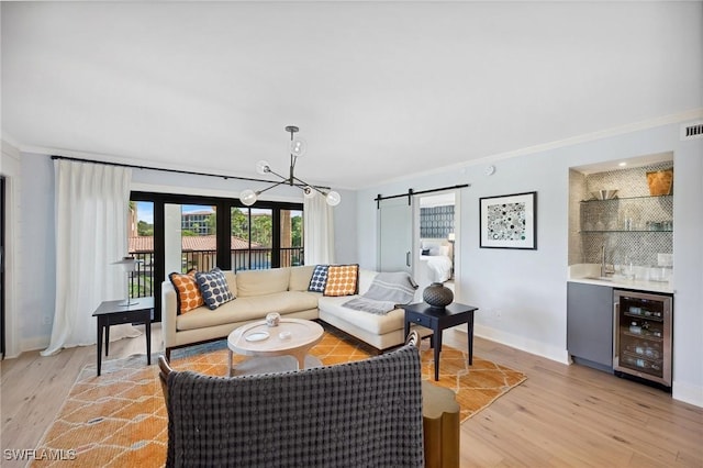 living room with a barn door, wet bar, light wood-type flooring, and wine cooler